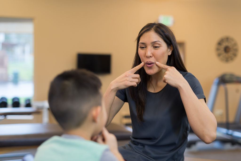 Speech therapist works with a young ethnic boy