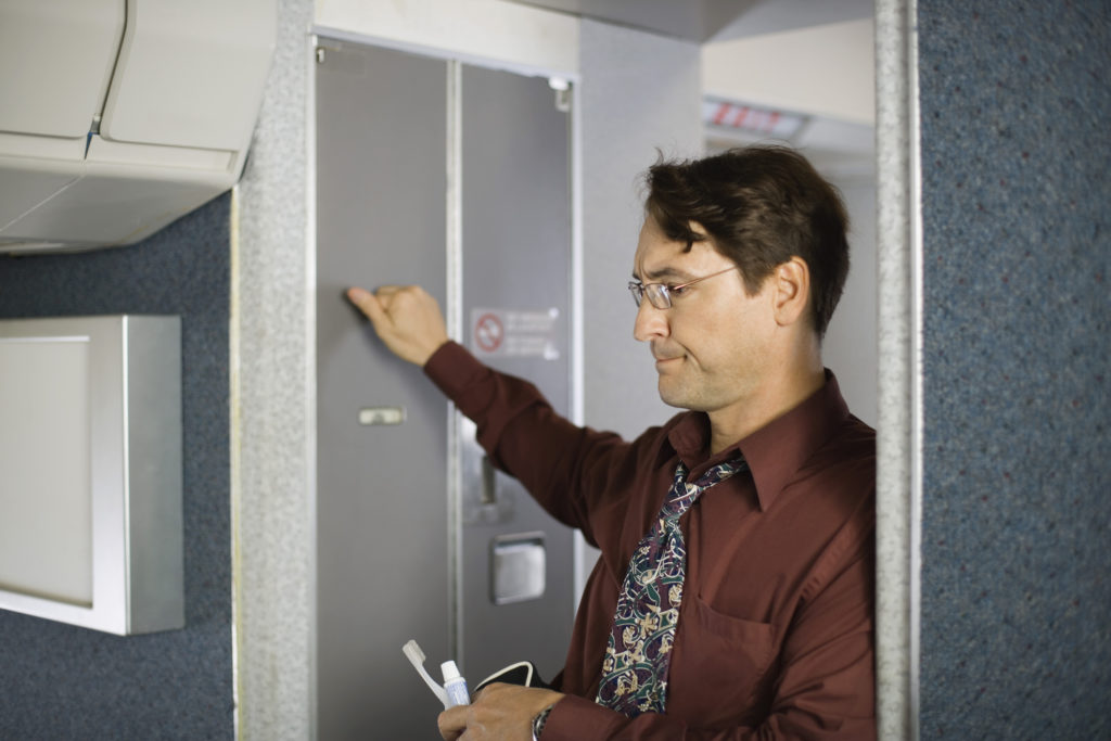 Passenger knocking on lavatory door on airplane