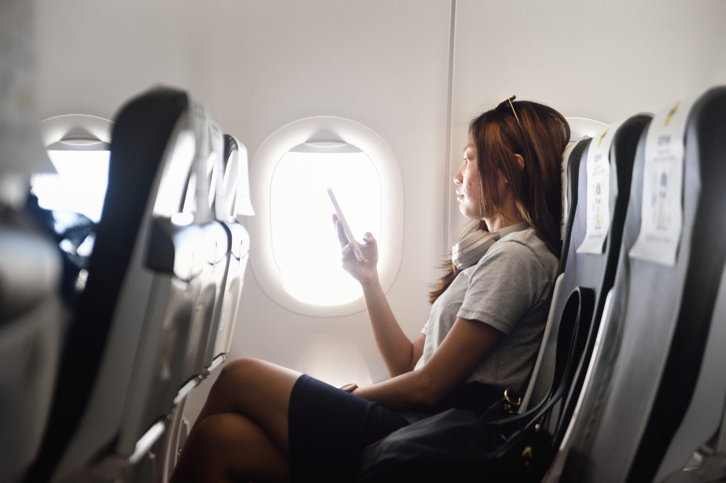 Business woman using her phone on a plane